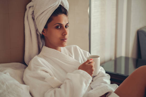 Girl in bathrobe with towel on her hair drinking coffee stock photo