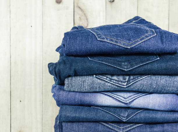 istock jeans stacked on wooden floor. blank background for design and text input. 973973488
