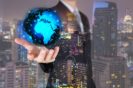 Double exposure of businessman hold the digital globe and night cityscape background as business, technology, communication and saving world concept.