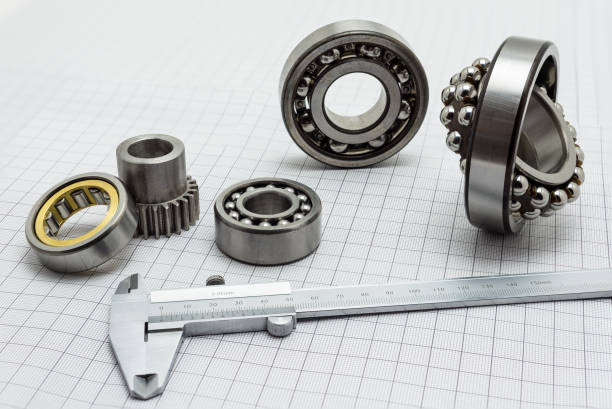 Vernier caliper lying on drafting paper with bearing and small gear.