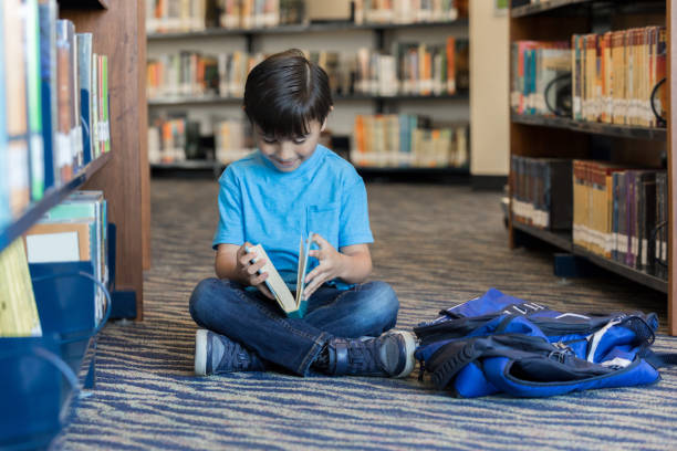 istock Little boy reads in library 973983360