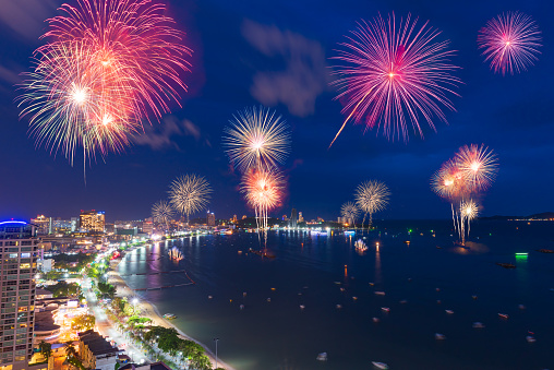 Fantastic and colorful fireworks over the sea and city with blue twilight sky background and city view in new year celebration night at Pattaya, Chon Buri, Thailand.