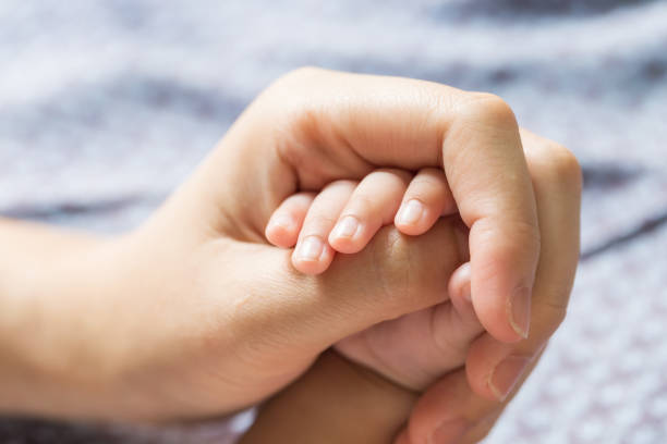 istock Baby hand holding finger mom. (Selected focus) 973985158