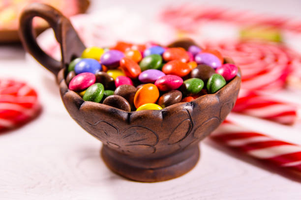 istock Ceramic bowl with colored candies, lollipops and marshmallows on a wooden table 973988992