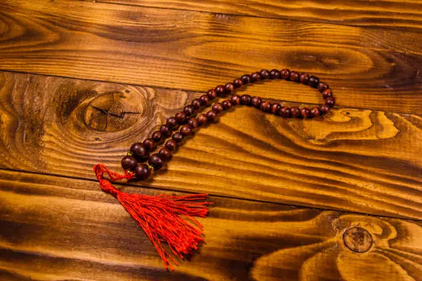 Photo of Brown rosary on the wooden table. Top view