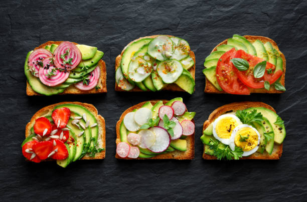istock Avocado sandwiches, toasts with various vegetarian toppings on a black stone background 974002732