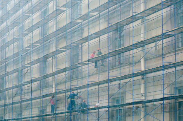 bauarbeiter auf dem gerüst. reparatur der fassade eines mehrstöckigen gebäudes. - restoring house scaffolding history stock-fotos und bilder