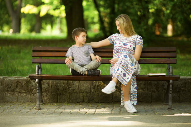 istock Mother and son in park outdoors sitting on the bench 974004056