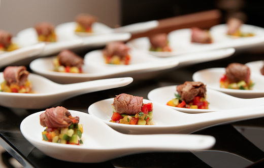 Small rolls of roast beef with vegetables on banquet table