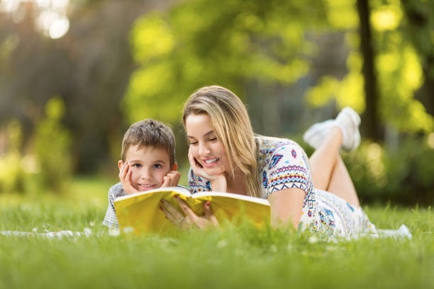 istock Mother and son reading a book in park 974009604