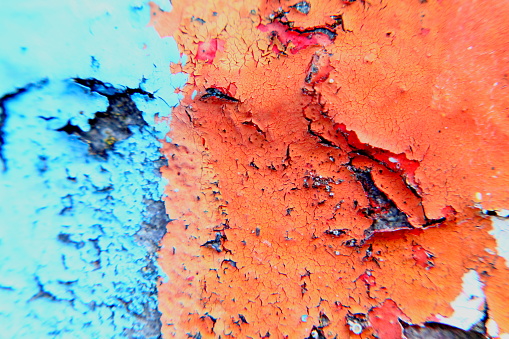 Macro light blurry photo of painted wall with red and blue cracked color surface.