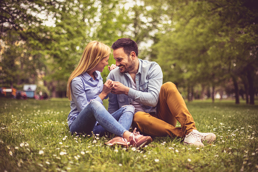 Young happy couple sitting on grass and talking.