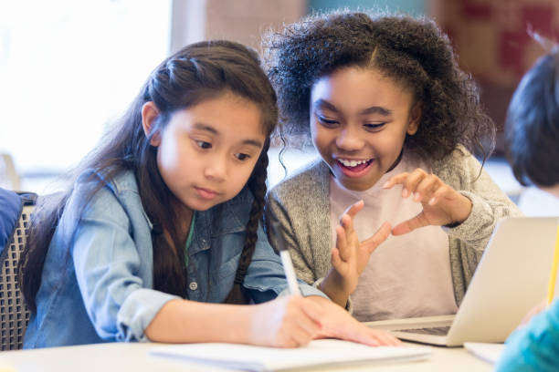 Excited schoolgirls work together in class