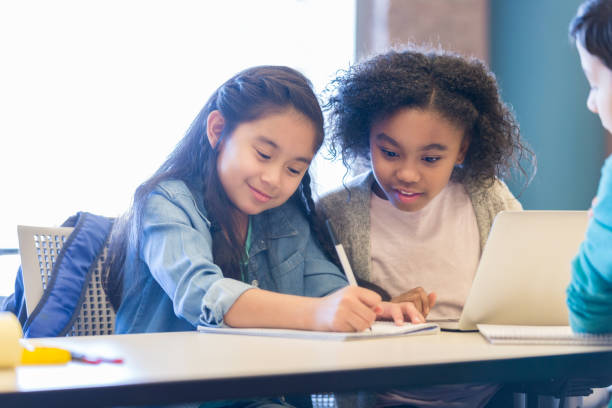 istock Cute schoolgirls work in class together 974018410