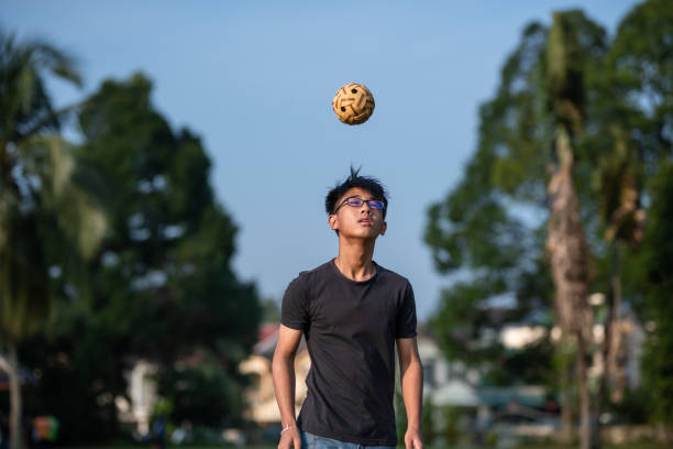 asia adolescente chino jugando sepak takraw en un día soleado - sepak takraw fotografías e imágenes de stock