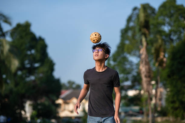 asian chinese teenage boy playing sepak takraw in a sunny day - sepaktakraw imagens e fotografias de stock