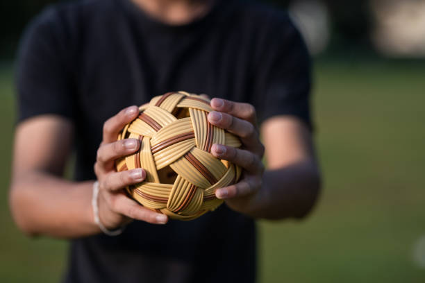 asian chinese teenage boy holding a sepak takraw in his hand - sepaktakraw imagens e fotografias de stock