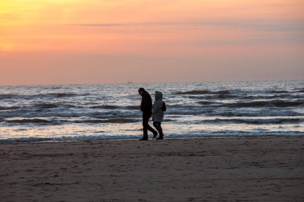 Katwijk, Netherlands - April 23, 2017: Man and woman walking on beach at sunset. Katwijk aan Zee. Netherlands