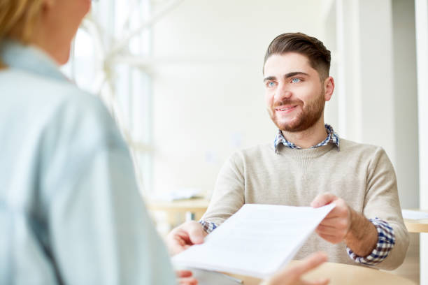 istock Young man giving paper to person opposite 974122998