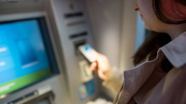 istock young woman inserting a credit card to ATM 974137940