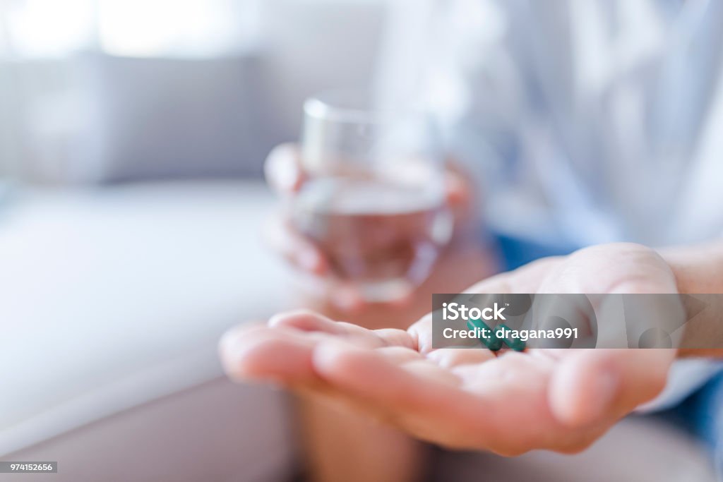 Man takes medicines with glass of water. Headache hand with pills medicine tablets and glass of water. Man takes medicines with glass of water. Daily norm of vitamins, effective drugs, modern pharmacy for body and mental health concept Capsule - Medicine Stock Photo