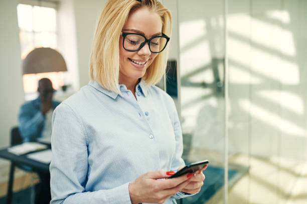 istock Smiling young businesswoman reading a text message in an office 974161386