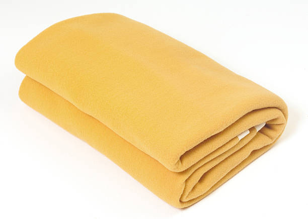 A soft yellow blanket folded up on a white background