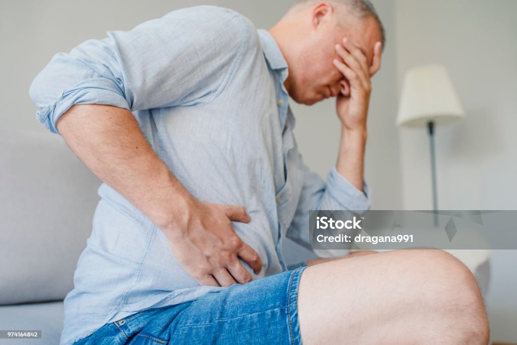 Terrible stomachache Terrible stomachache. Frustrated handsome young man hugging his belly and keeping eyes closed. Disturbed male having pain in stomach Liver - Organ Stock Photo
