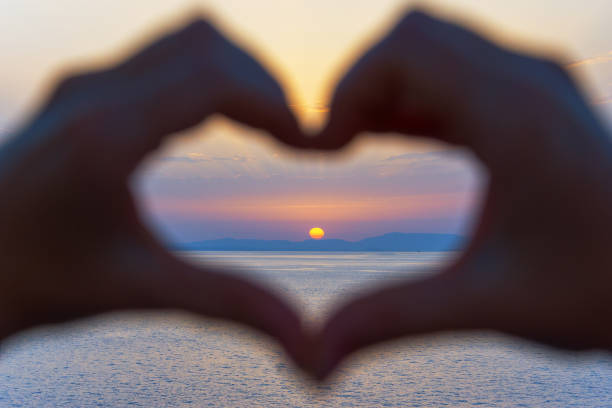 istock Hands forming a heart shape with sunset silhouette 974165440