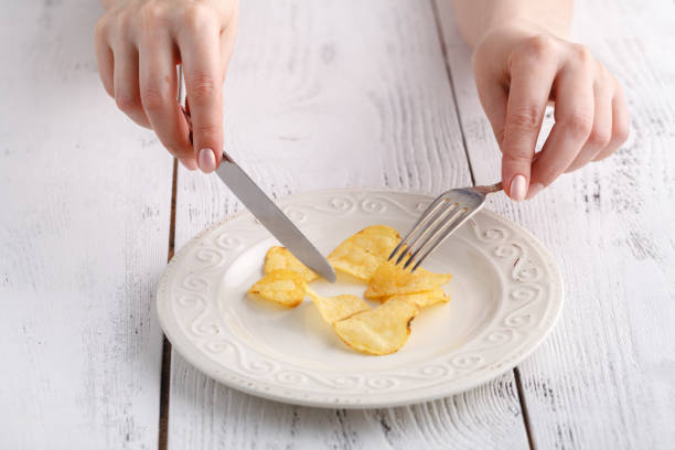 istock Female eat potato chips with fork on plate 974174632