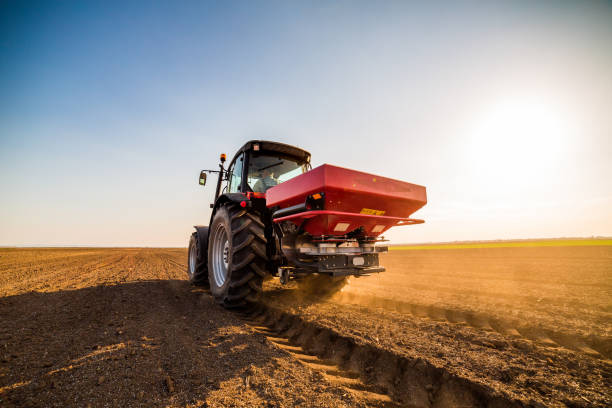 istock Farmer fertilizing arable land with nitrogen, phosphorus, potassium fertilizer 974175314