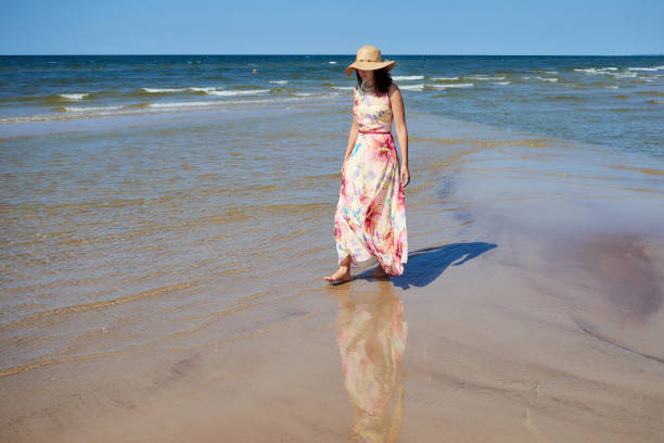 istock A relaxed girl with a hat goes along the beach. 974176124