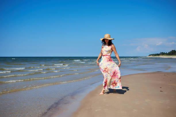 istock A relaxed girl with a hat goes along the beach. 974176126