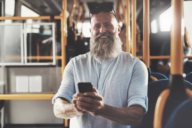 istock Smiling man with a beard reading texts on the bus 974176164