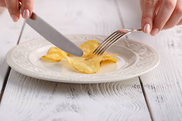 istock Female eat potato chips with fork on plate 974178230