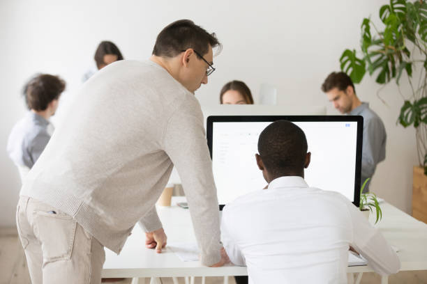 istock Senior mentor helping African American colleague with pc 974191640