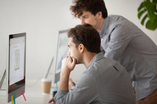 istock Caucasian male coach helping colleague with computer issues in office 974191898