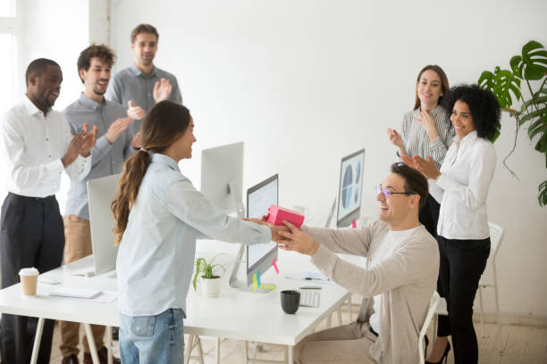 istock Diverse colleague congratulating male coworker with gift box 974191986