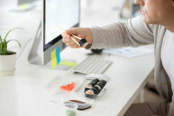 Close up of male employee enjoying sushi at workplace