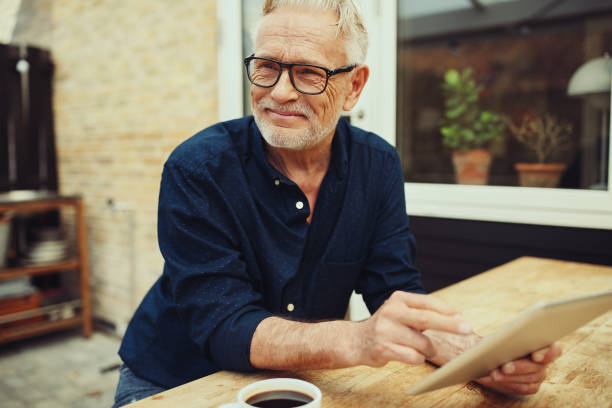 istock Senior man sitting outside drinking coffee and using a tablet 974225884