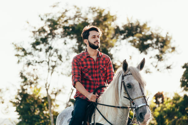 istock Young man riding white horse on the countryside 974231472