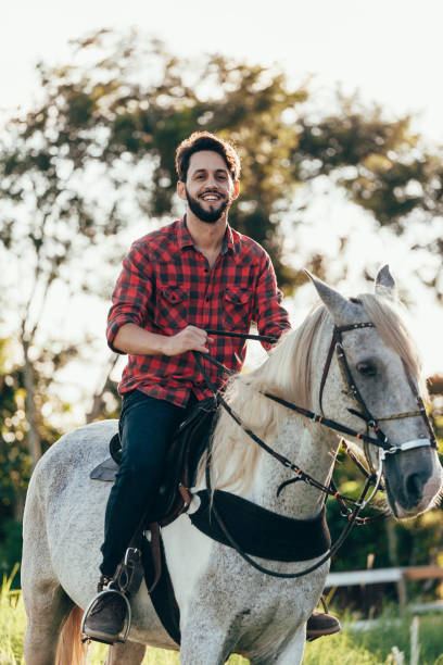 istock Young man riding white horse on the countryside 974231856