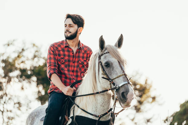 istock Young man riding white horse on the countryside 974232238