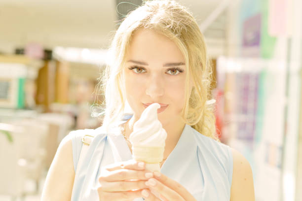 Portrait of a beautiful girl in the hallway of the shopping center with a horn of ice cream in his hands and a beautiful look.