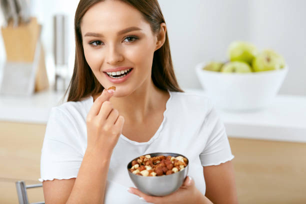 istock Healthy Nutrition. Beautiful Young Woman Eating Nuts 974257568