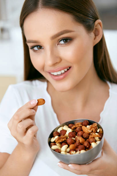 istock Smiling Woman Eating Nuts In Kitchen 974257924