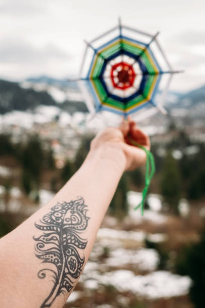 Stretched hand with henna tattoo holding knitted mandala