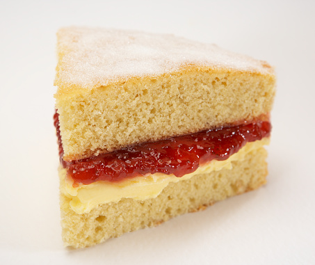 SINGLE SLICE OF JAM AND CREAM SPONGE CAKE ON WHITE BACKGROUND