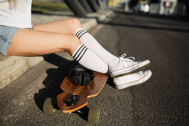istock Girl rest on sidewalk after riding on longboard 974289500