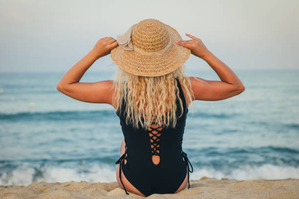 istock Woman with hat relaxing on beach, looking at sea. Copy space 974339242